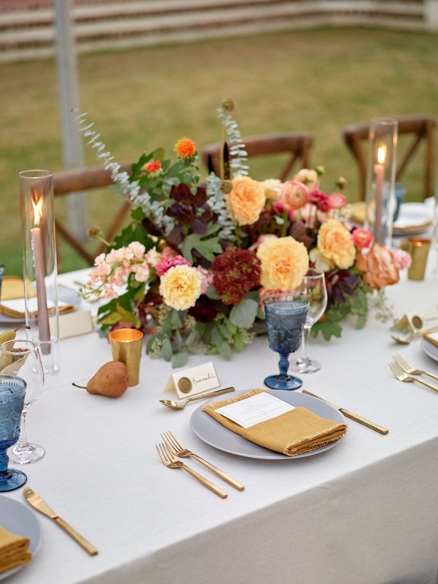 wedding table with floral arrangement, candles, and dining settings